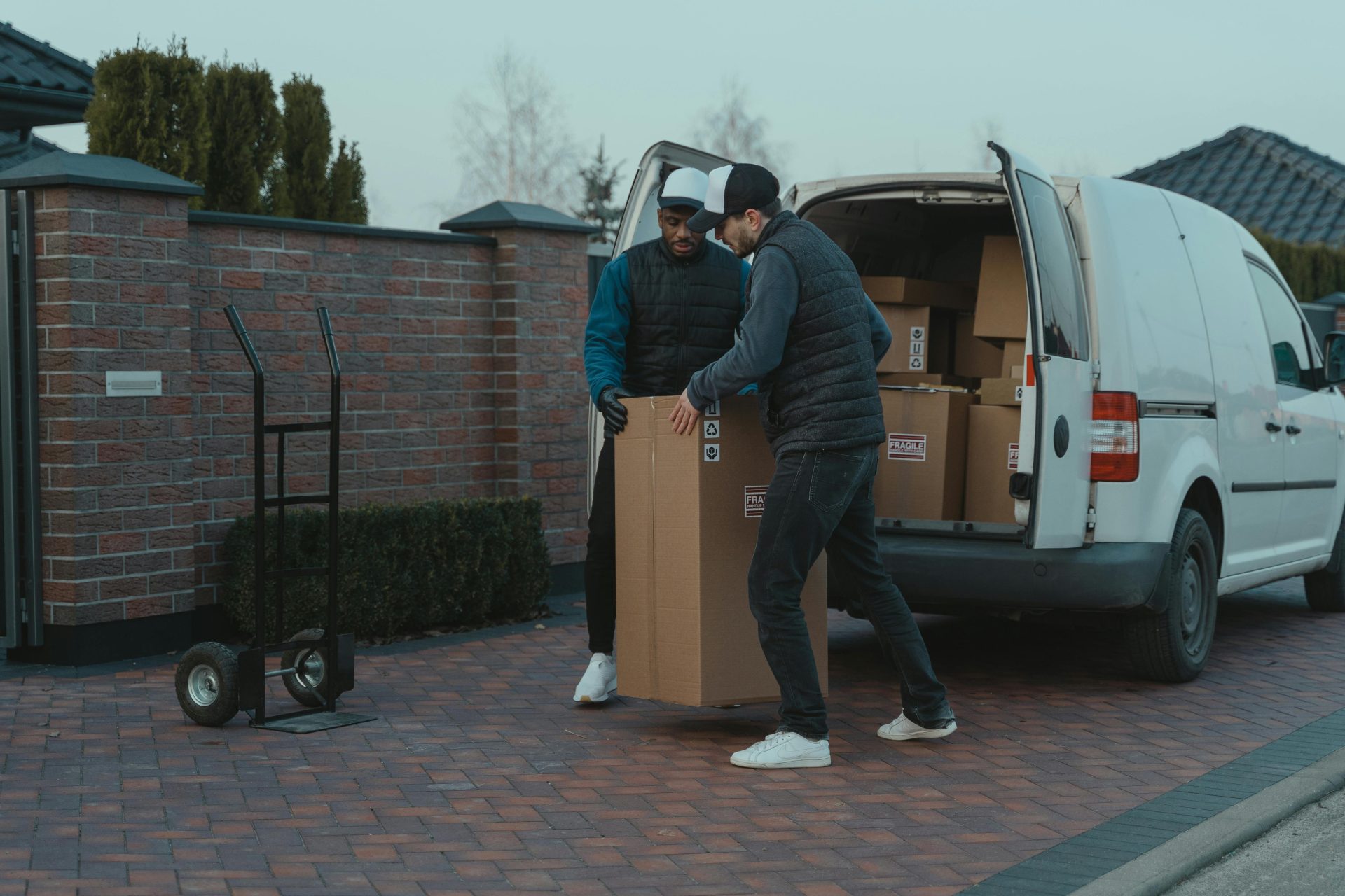 Zustellteam verlädt Pakete aus einem Lieferwagen in einem Vorstadtgebiet.
